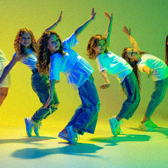 Group of active kids, cheerful girls dancing isolated over green background in neon light